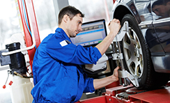 Auto Mechanic at wheel alignment work with spanner
